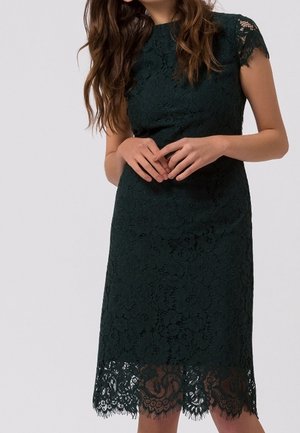 Dunkelgrünes Spitzenkleid mit hohem Ausschnitt, kurzen Ärmeln und dekorativem Spitzenabschluss am Saum. Der Stoff ist mit floralen Mustern strukturiert.