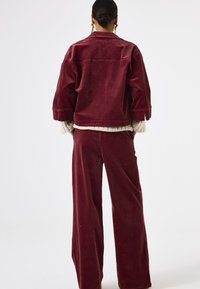 Bordeaux corduroy jacket met een relaxte fit, voorzien van wijde mouwen en een gestructureerde binnenvoering, gecombineerd met bijpassende wijde broek.