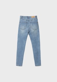 Light blue jeans with a slim fit, featuring five pockets, visible stitching, a leather patch at the waistband, and a slightly faded texture.