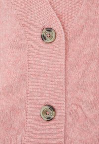 Cardigan en tricot rose avec une finition texturée, un décolleté en V et deux boutons ronds marbrés à l'avant.