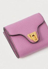 Pintas su iškilimais rožinis odinis piniginė su juodu apvadu ir auksiniu užsegimu ant šviesaus fono.