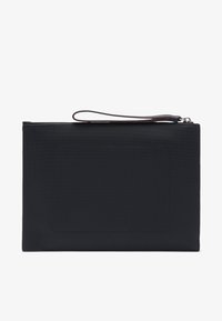 Pochette noire texturée avec une sangle pour le poignet, dotée d'une fermeture éclair lisse, d'une forme rectangulaire épurée et d'un patch central vide.