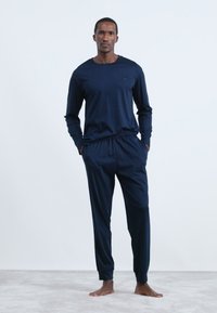 Mörkblå långärmad topp som matchas med lätta joggers, med elastisk midja och en mjuk, slät textur.