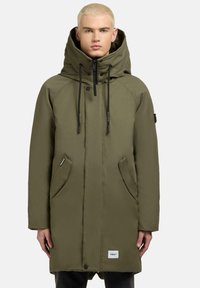 Parka oliva con colletto alto, chiusura con zip, due tasche frontali e cappuccio regolabile. Tessuto liscio e resistente con dettagli del logo.
