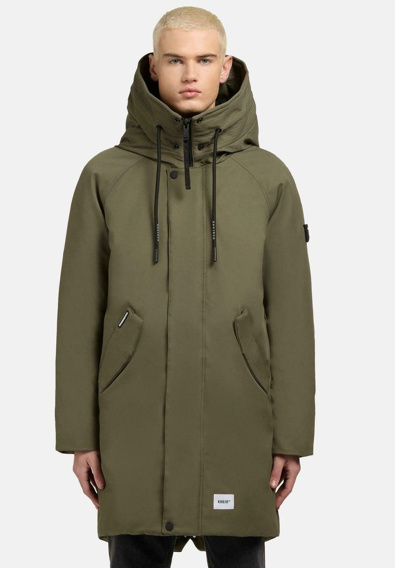 Parka oliva con colletto alto, chiusura con zip, due tasche frontali e cappuccio regolabile. Tessuto liscio e resistente con dettagli del logo.