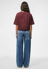 Bordeaux gebreid top met korte mouwen, gecombineerd met hoge taille, wijde blauwe denim jeans, met een vervaagde textuur en klassieke vijf-pocket ontwerp.