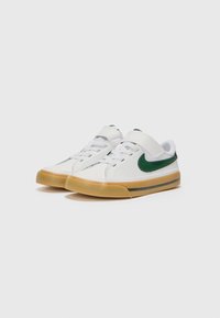 Sneakers med vit syntetisk ovandel, grön Nike Swoosh och tan gummisula. Har en kardborreband och traditionella snören för stängning.