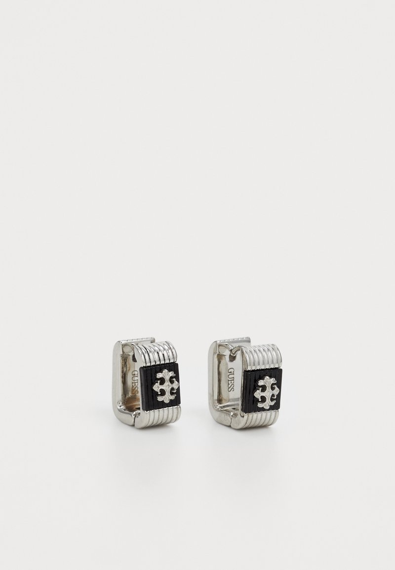 Cercei de manșetă cu ton argintiu, având un centru dreptunghiular negru, prezentând un design decorativ embosat și margini striate.