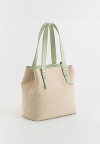 Bolsa tote beige con tela texturizada, asas de cuero verde menta y acentos de hardware dorado. Forma cuadrada con detalles cosidos.