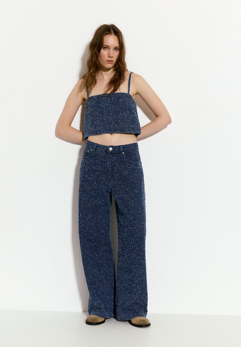 Modrý puntíkovaný cropped top s tenkými ramínky a vysokým pasem široké kalhoty ze stejných materiálů. Měkká textilie a volný střih po celém kroji.