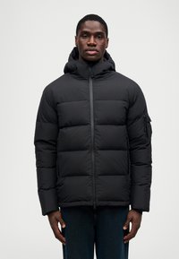 Jachetă puf într-o nuanță neagră, cu fermoar pe față, glugă reglabilă și manșete elastice. Dispune de un buzunar pe piept cu fermoar. Design texturat, izolat.