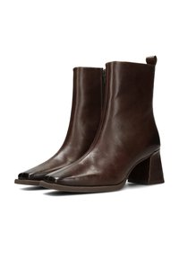 Par de botines de cuero marrón oscuro con punteras cuadradas, tacones anchos y cremalleras laterales, exhibidos sobre un fondo blanco.