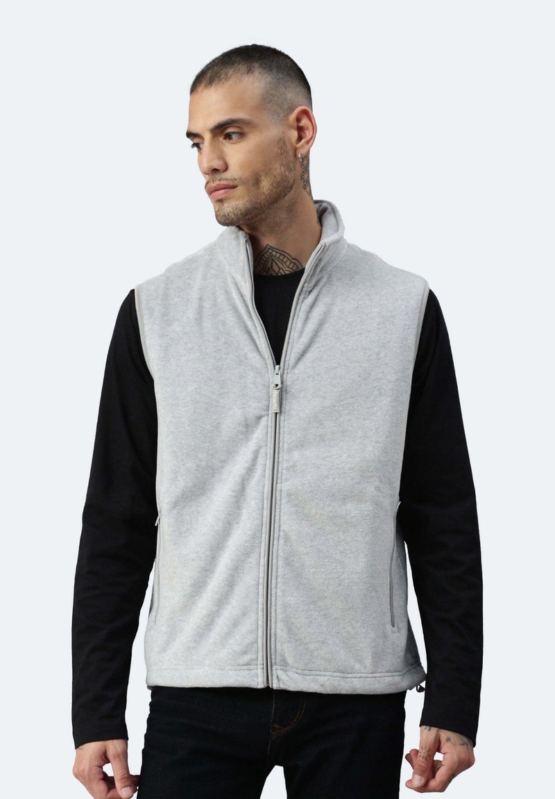 Grau Fleece-Weste mit hohem Kragen, durchgehendem Reißverschluss, Seitentaschen und lockerer Passform, getragen über einem schwarzen Langarmshirt.