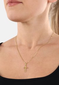 Collana con pendente a croce dorata su una catena sottile, caratterizzata da una finitura lucida e un design minimalista, indossata all'altezza del collo.