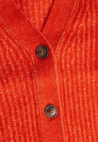 Cardigan rosso lavorato a maglia con coste testurizzate, caratterizzato da un profondo scollo a V e un bottone scuro al centro frontale. Tessuto morbido e caldo.