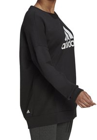 Sudadera negra de corte holgado, con un logo blanco de Adidas en el frente y puños de canalé. Fabricada con tejido suave, con detalle de logo acentuado.
