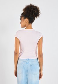 Tricou roz deschis, aderent, cu mâneci scurte, asortat cu o fustă din denim albastru deschis, cu talie înaltă. Material moale, textură netedă, design simplu.