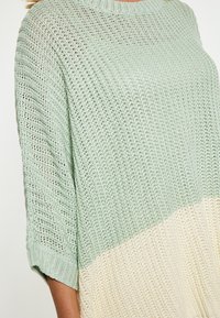 Pullover in maglia con un design a gradiente, che passa dal verde chiaro al crema, con una vestibilità ampia e un tessuto testurizzato e traspirante.