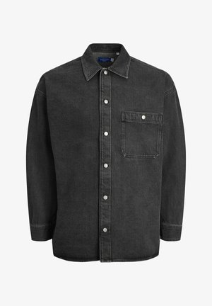 Crna traper košulja dugih rukava, s raširenim ovratnikom, gumbićima sprijeda i jednom džepom na prsima. Ima srebrne kopče na dugmadima i ležeran kroj.