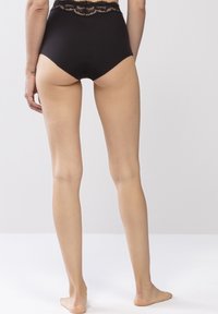 Höga svarta trosor med spetsdetalj i midjan; slätt tyg; kroppsnära passform, minimalistisk design och inga synliga mönster.