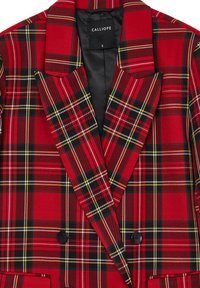 Blazer a quadri rossi con dettagli neri e gialli, dotato di design doppiopetto, rever a scollo a V e fodera nera. Nome del marchio visibile.