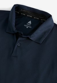 Marineblå polo skjorte lavet af struktureret stof, med en klassisk krave, tre-knaps placket og en logoet inderskilt.