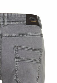 Jeans en denim gris avec une finition texturée, dotés d'une poche arrière et d'une étiquette noire avec le logo "Camel Active" sur la taille.