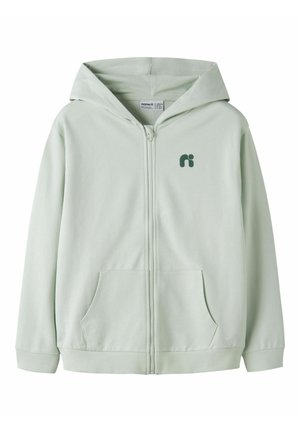 Svetlo zelena jopa s kapuco z zadrgo po celotni dolžini, sprednjimi žepi, rebrastimi manšetami in spodnjim robom, kapuco ter malim temno zelenim logotipom na zgornji levi strani prsnega koša.