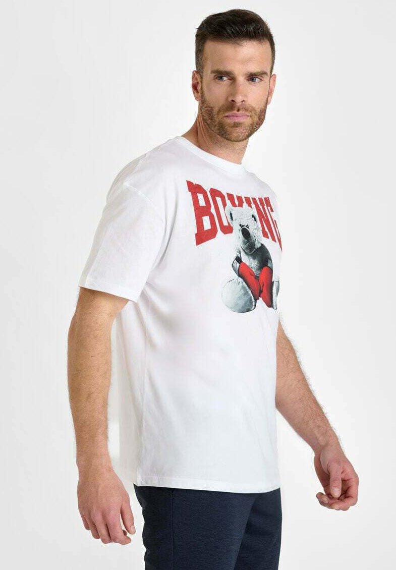 Camiseta de algodón blanca con un gráfico de un oso boxeando con corazones rojos, la palabra "BOXING" en letras rojas en negrita arriba. Mangas cortas, corte holgado.