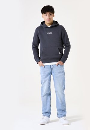 Hoodie gris foncé avec poche avant, texte blanc "OBJECTIFS FUTURS", associé à un jean bleu clair et des baskets blanches. Tissu doux, coupe décontractée.