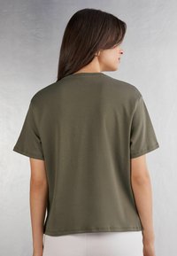 Olivově zelené tričko s krátkým rukávem vyrobené z měkké látky, s uvolněným střihem, kulatým výstřihem a minimálními švy na lemu.
