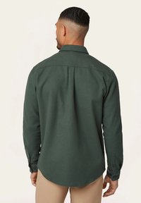 Donkergroene, langärmige shirt met een kraag, knoopmanchetten en een gladde, textuurstof. Beschikt over een achteryoke en een gebogen zoom.