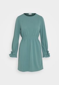 Sininvihreä mekko, joka on tehty sileästä kankaasta. Siinä on pyöreä pääntie, kerrostettu vyötärö ja pitkät hihat, joissa on solmimisnauhat hihansuiden kohdalla.