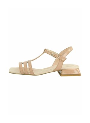 Sandale T-strap en cuir verni nude avec trois fines brides avant, une bride de cheville ajustable et un talon carré. Texture de surface lisse.