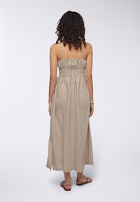 Abito maxi beige con corpino arricciato, spalline sottili e spacco laterale. Realizzato in tessuto testurizzato, arriva alla caviglia e ha una vestibilità comoda.