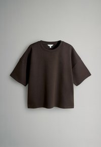 Tumši brūns īsām piedurknēm T-krekls, kas izgatavots no kokvilnas. Brīvreizējo piegriezumu ar apaļu kakla izgriezumu un nolaižamām plecu šuvēm, ar gludu tekstūru.