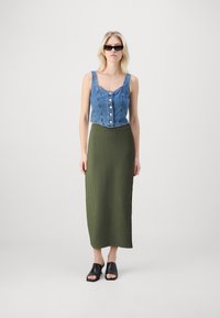 Denim vrhnji del s gumbi, rebrast olivno zelen maxi krilo in črne mule z odprtimi prsti. Ima naramnice in prilegajoč dizajn s stranskimi razporki.