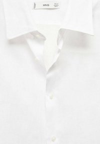 Witte button-up shirt gemaakt van een lichtgewicht stof. Heeft een klassieke kraag, subtiele textuur en vier witte knopen op de knoopsluiting.