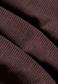 Brown ribbed fabric showing fine vertical textures; soft, fuzzy surface with a consistent pattern and rich coloration.