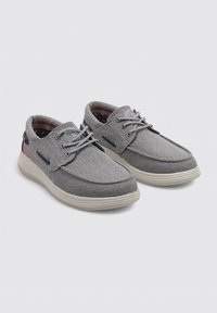 Zapatos de tela grises con una textura suave, diseño de cordones, suela de goma blanca y acentos en azul y rojo contrastantes cerca del talón.