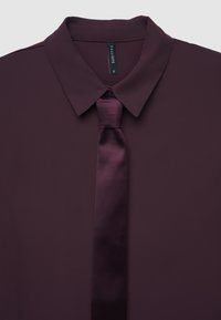 Camicia bordeaux con colletto e cravatta in raso abbinata. Tessuto morbido e texturizzato, con chiusura a pulsante e una lucentezza sottile. Taglia: S.