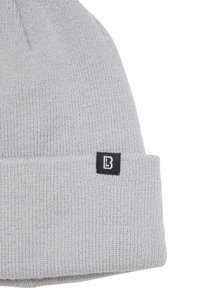 Căciulă gri tricotată, cu tiv pliat. Dispune de o etichetă mică neagră cu un logo alb pe lateral. Țesătură texturată cu aspect moale.