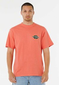 T-shirt di cotone corallo con maniche corte e scollatura rotonda. Presenta una piccola grafica verde e blu sul lato sinistro del petto.