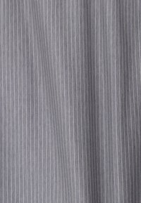 Tissu gris avec de fines rayures verticales blanches et une texture tissée subtile, délicatement drapé avec des plis doux.