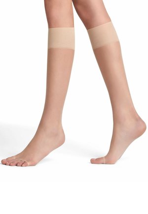 Chaussettes hautes beiges en voile avec une texture lisse, un design à bout ouvert et des bandes en silicone en haut pour un maintien sécurisé.