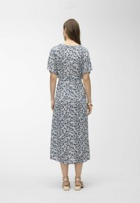 Modré a bílé květinové midi šaty s krátkými rukávy, zúženým pasem a splývavou sukní. Měkká, lehká tkanina s jemným vzorem.