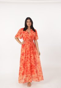 Maxiklänning i orange tyg med blommönster. Har korta ärmar, v-ringning, smockad midja och en följsam silhuett.
