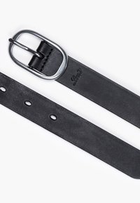 Ceinture en cuir noir avec boucle ovale en argent et détails cousus, présentant un logo en relief près de la boucle et plusieurs trous d'ajustement.