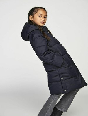 Cappotto imbottito blu navy con cappuccio, caratterizzato da un design trapuntato, risvolti laterali e un taglio di lunghezza media. Abbinato a jeans grigi e stivali neri.