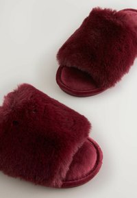 Burgunderfarvede faux fur hjemmesko med en blød tekstur, bred toprem og en polstret sål, designet til komfort og varme.